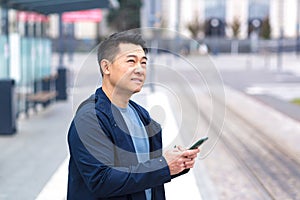 Thinking Asian, business man uses phone, near modern office, and airport