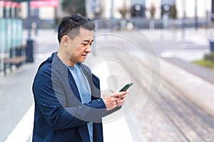 Thinking Asian, business man uses phone, near modern office, and airport