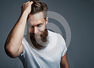 Thinking bearded man holding hair and laughing