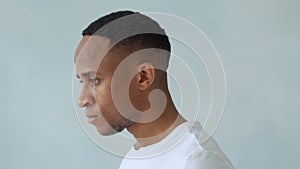 Thinking black Afro American man with serious expression looking with eyes directly into camera while posing against