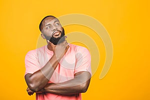 Thinking black Afro American man with serious expression looking, posing isolated against yellow background