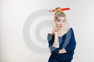 Thinking blonde woman having big pencil in hair