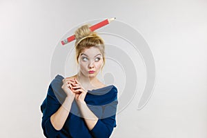 Thinking blonde woman having big pencil in hair