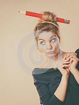 Thinking blonde woman having big pencil in hair