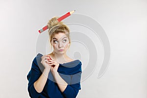 Thinking blonde woman having big pencil in hair