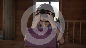 Thinking boy at the table near the tablet clutching his head, insoluble situation