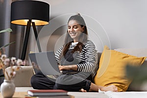 Thinking of bright future attractive student female working on laptop at home cheerful smiling