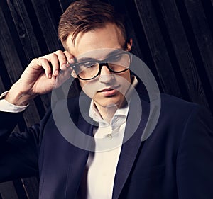 Thinking business man looking down in suit and trendy eyeglasses