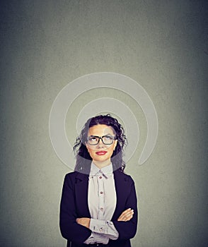 Thinking business woman in glasses looking up