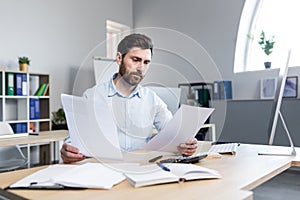 Thinking businessman working with documents in the office, man reviewing financial reports