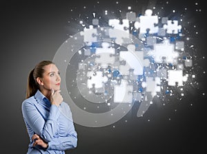 Thinking businesswoman looking at shining puzzle pieces photo