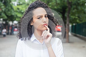 Thinking caribbean woman with curly hair in a park