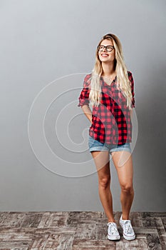 Thinking cheerful young blonde woman standing isolated