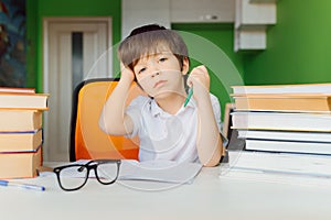 Thinking child bored, frustrated and fed up doing his homework