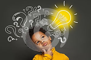 Thinking child boy on black background with light bulb and question marks. Brainstorming and idea concept photo