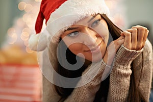 Thinking about Christmases past. an attractive young woman wearing a santa hat looking thoughtful.