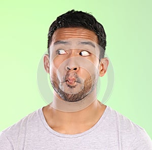 Thinking, crazy and face of funny man in studio with pastel green background for weird comedy. Silly, joke and