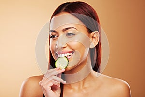 Thinking, cucumber and woman with skincare, dermatology and cosmetics on a brown studio background. Female person