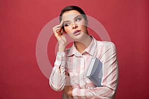 Thinking doubting woman with book on red background