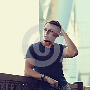 Thinking handsome young man looking on city center background wi