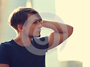 Thinking handsome young man looking on city center background wi