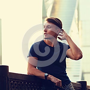 Thinking handsome young man looking on city center background wi