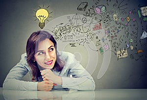 Thinking happy young business woman sitting at desk planning