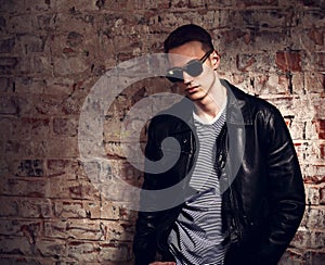 Thinking male model posing in leather jacket and trendy eyeglass