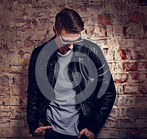 Thinking male model posing in leather jacket and trendy eyeglass