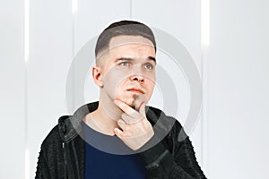 Thinking man holds hand at face, Closeup portrait of young pensive guy. Caucasian male model