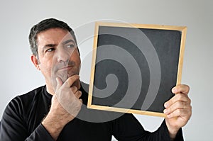 Thinking man looks at an empty blackboard