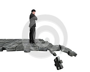 Thinking man standing on breaking puzzle ground