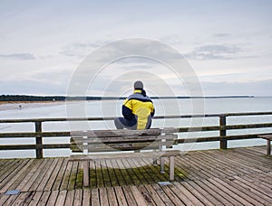 Thinking man on wooden pier on background of sea