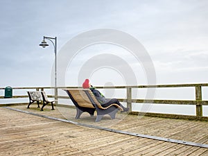 Thinking man on wooden pier on background of sea