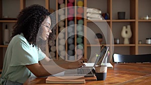 Thinking mixed-race businesswoman working on laptop computer in office interior