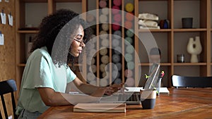 Thinking mixed-race businesswoman working on laptop computer in office interior