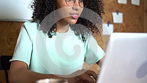 Thinking mixed-race businesswoman working on laptop computer in office interior