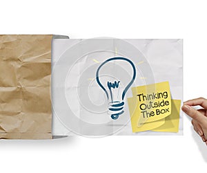 thinking outside the box on sticky note and lightbulb as creative on crumpled envelope paper