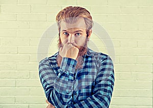 Thinking. Portrait of a worried man casual blue shirt man looking at you camera isolated white brick wall background. Yellow Toned