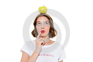 Thinking pretty caucasian woman holding apple on head