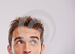 Thinking in progess. Studio shot of a handsome young man looking up. photo