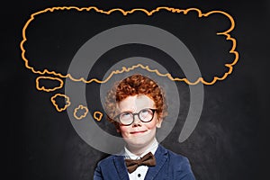 Thinking schoolboy and big empty speech cloud bubble on chalkboard background