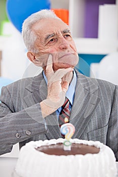Thinking senior man with birthday cake