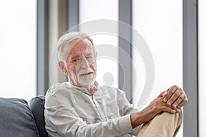 Thinking senior man sits on a couch in the living room, Worry elderly man