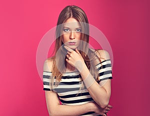 Thinking serious woman in striped dress looking on bright pink b