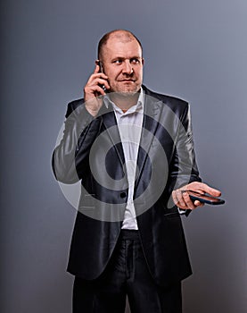 Thinking stressed angry doubt business man talking on mobile phone very emotional in office suit on grey background. Closeup