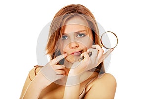 Thinking teenage woman holding magnifying glass