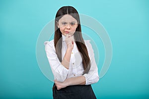 Thinking teenager girl, thoughtful emotion. Thoughtful teenage child girl on blue isolated background. Portrait of a kid