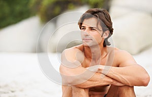 Thinking things over. Shot of a handsome young man enjoying a relaxing day at the beach.