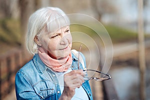 Serious old woman holding her glasses